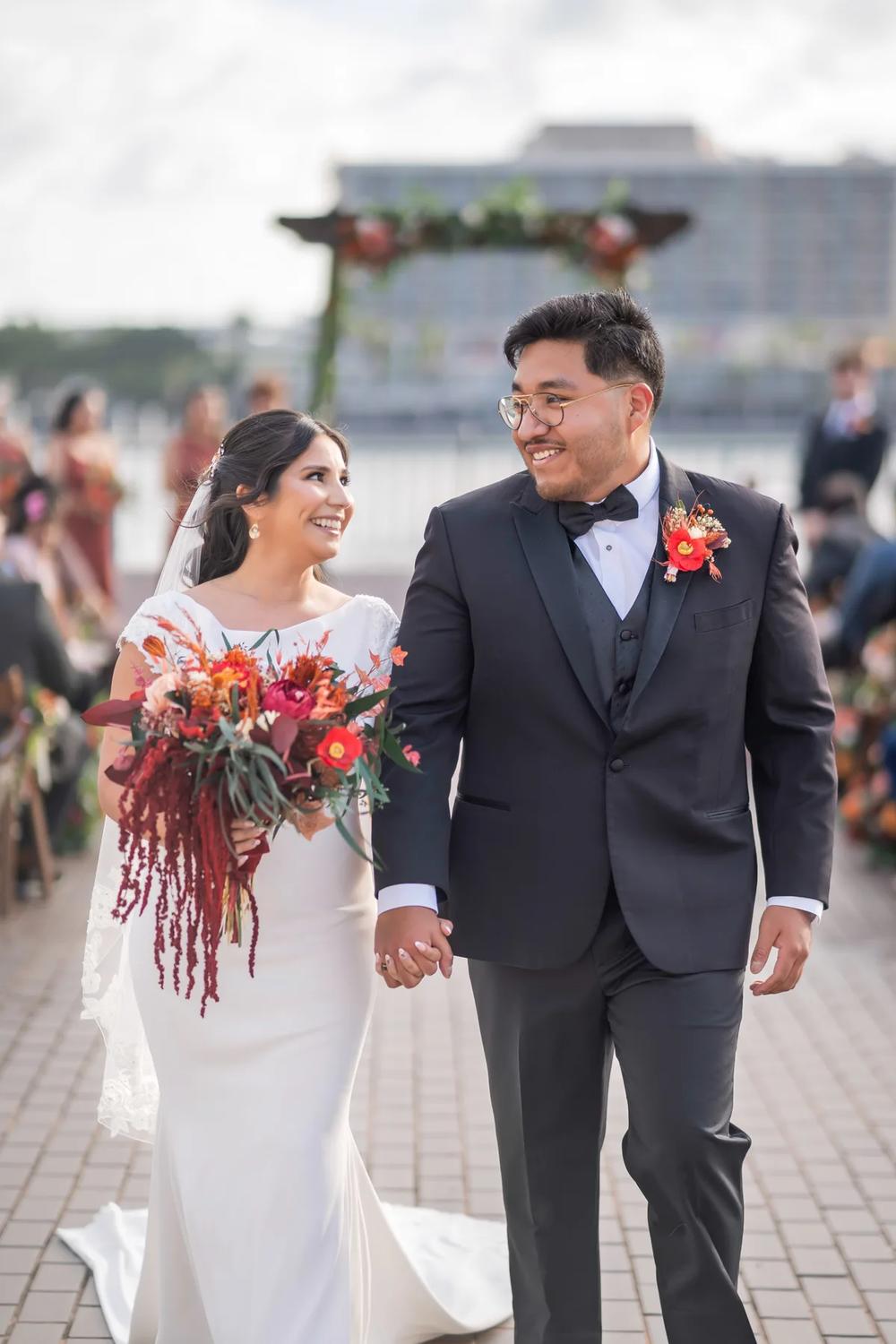 A bride and groom share a joyful moment during their wedding ceremony on an outdoor waterfront.