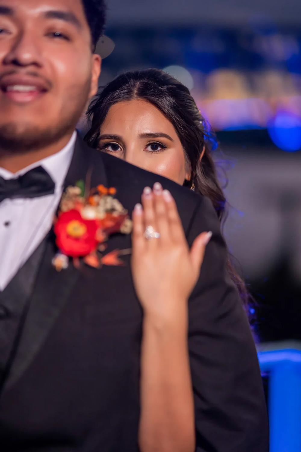 A bride and groom share a tender moment at their evening wedding reception under vibrant blue lighting.