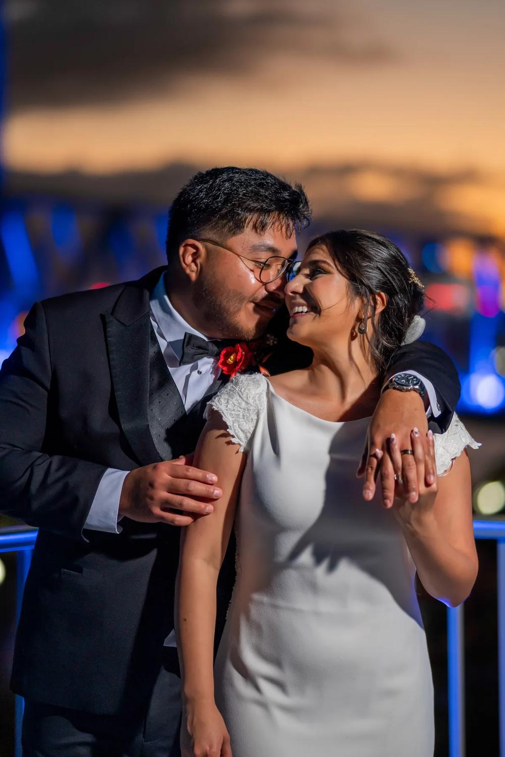 A bride and groom share a tender moment against the backdrop of a vibrant sunset.