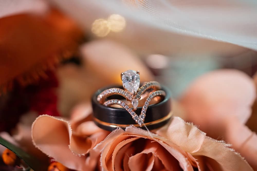 A close-up of a wedding ring set resting on a delicate fabric backdrop with soft lighting and romantic tones.