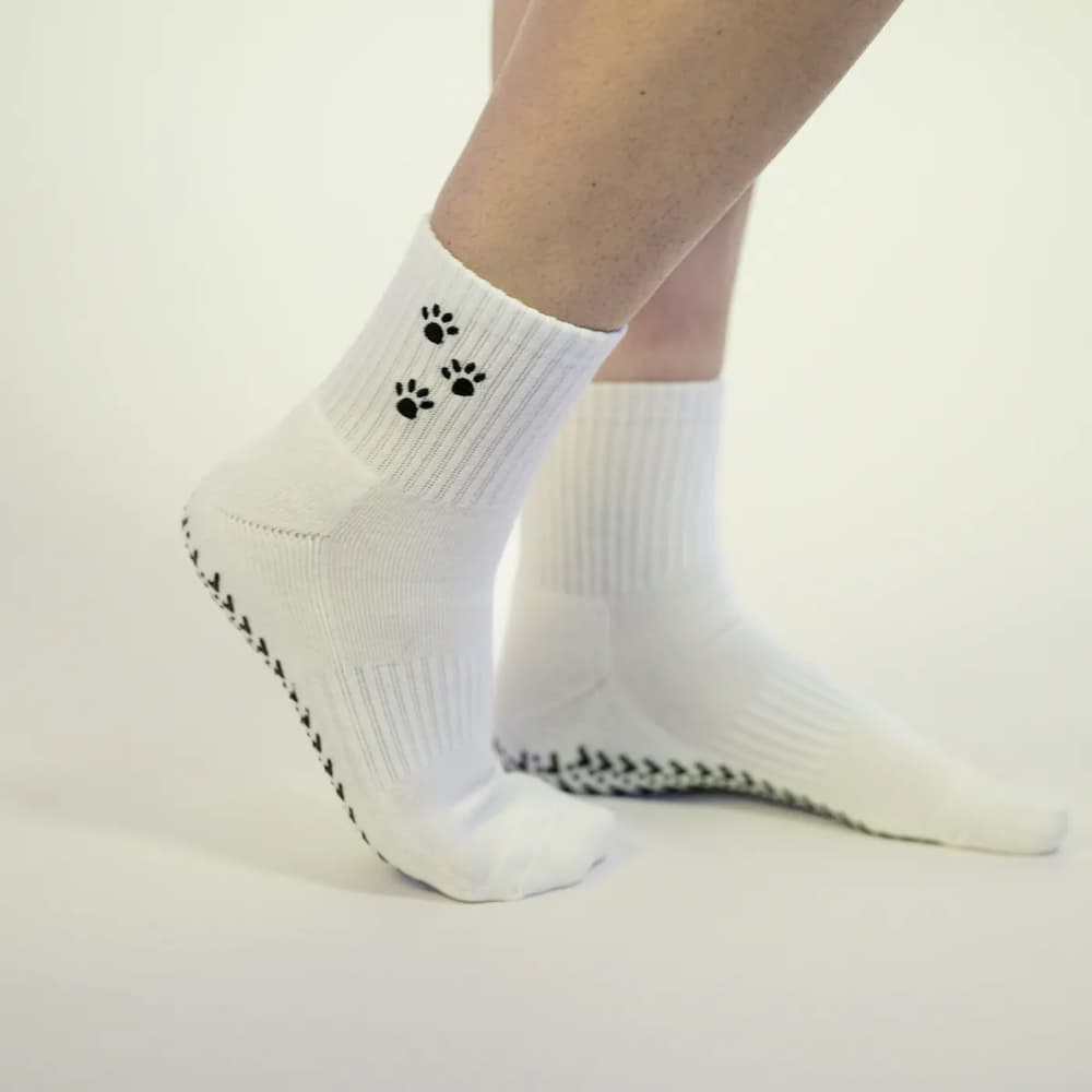 A close-up of white socks with black paw prints on a plain white background.