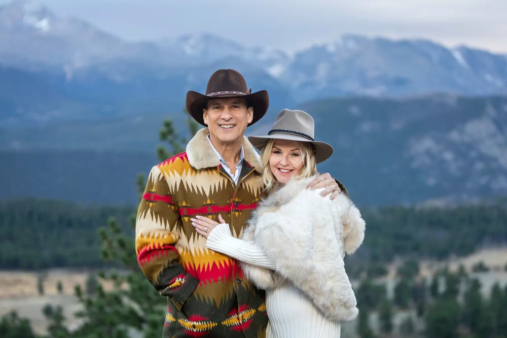 A couple embraces against a majestic mountain backdrop under soft, diffused lighting.