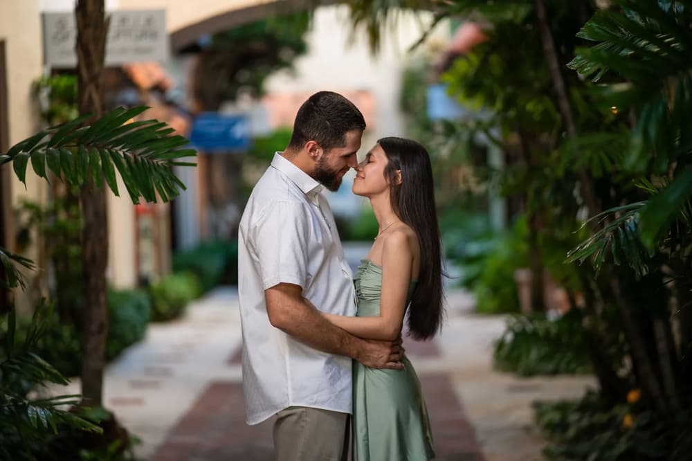 A couple shares an intimate moment in a lush tropical setting during the golden hour.