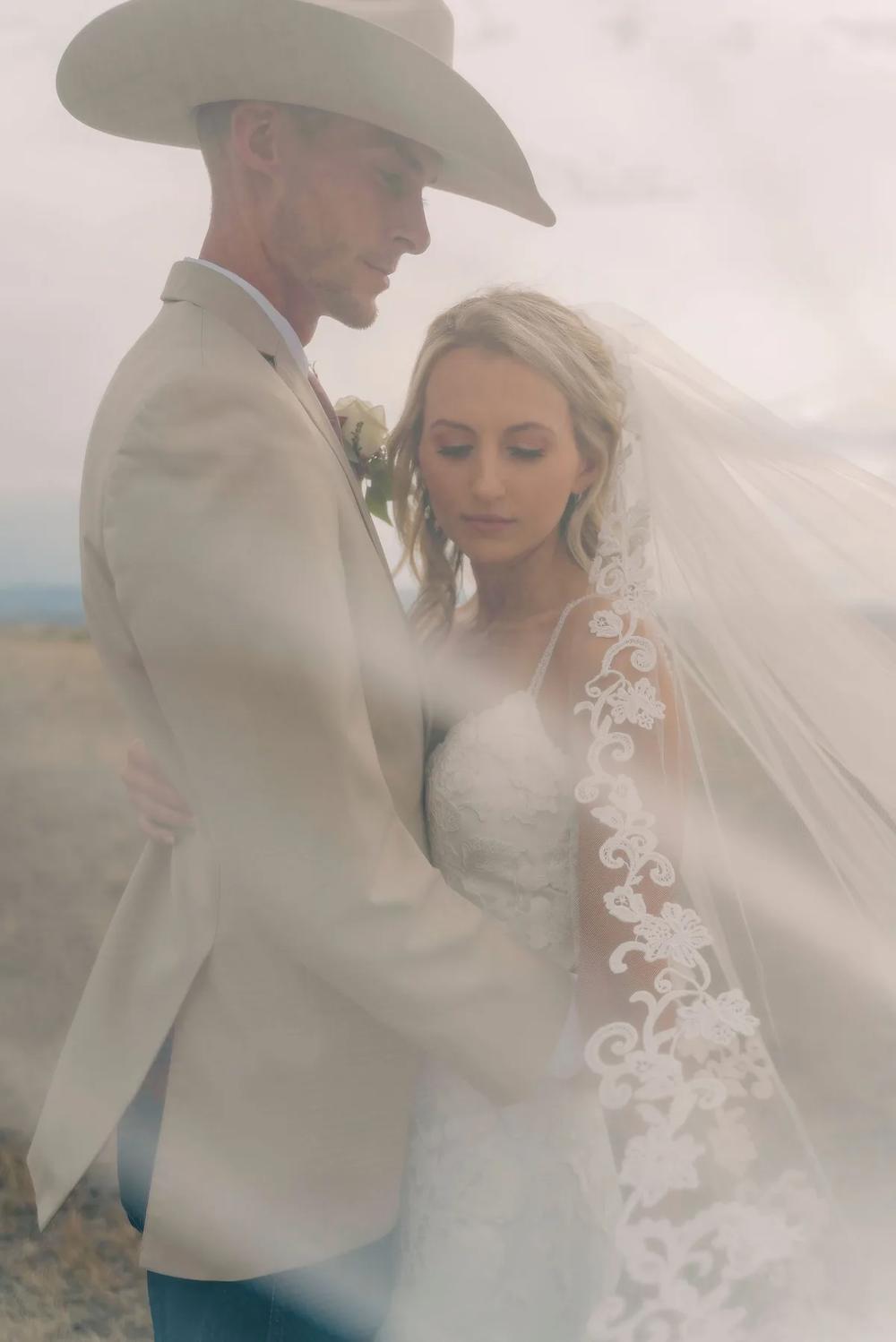 A bride and groom share a tender moment amidst a misty desert backdrop.