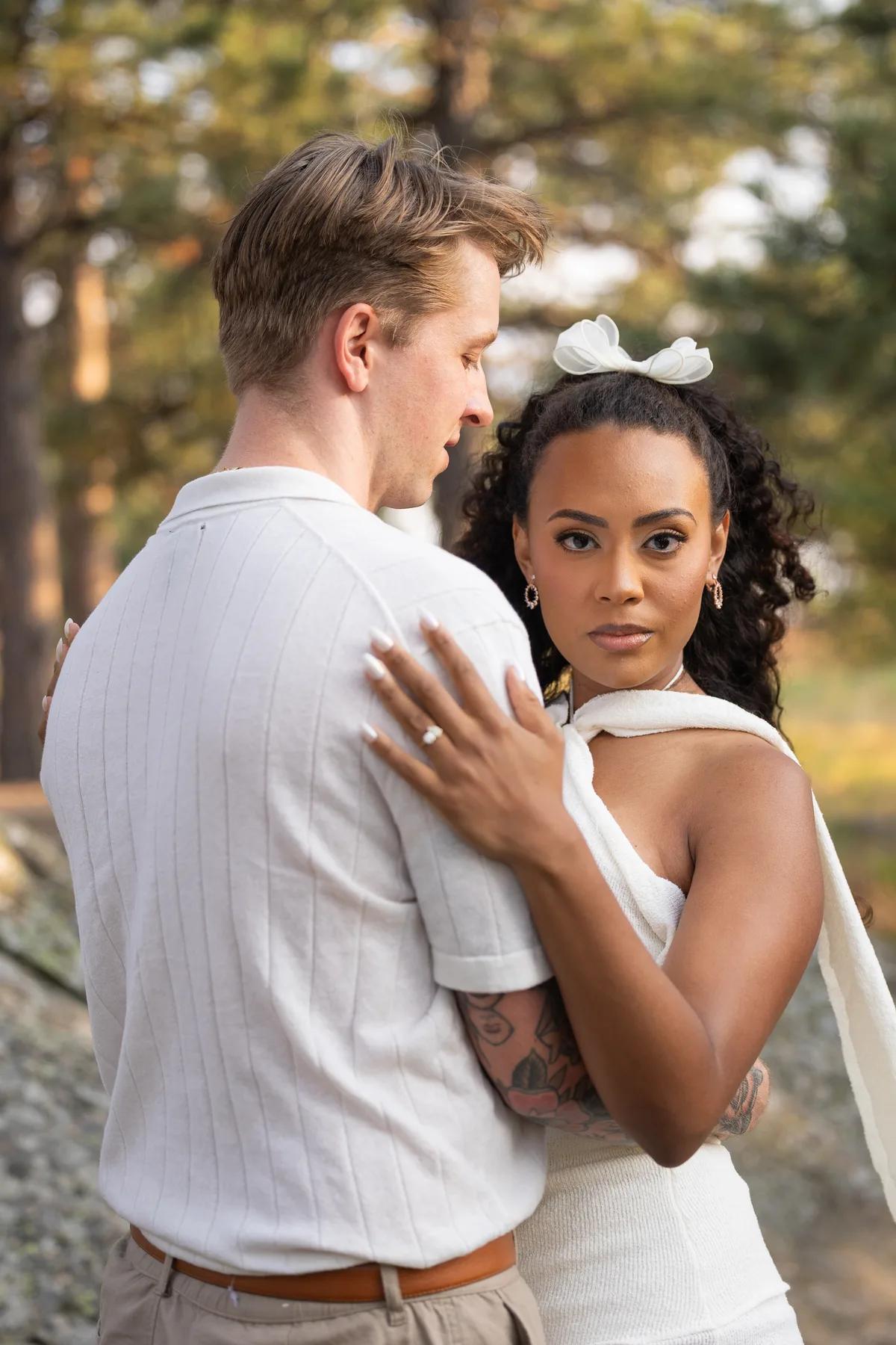 A tender embrace between a couple in a serene outdoor setting during golden hour.