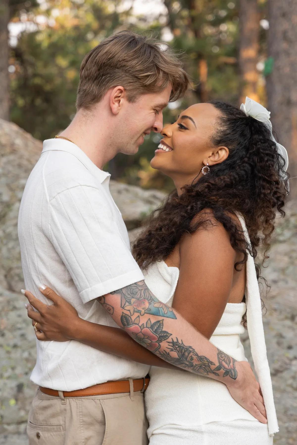 A couple embraces tenderly in a natural outdoor setting during the golden hour, exuding warmth and affection.