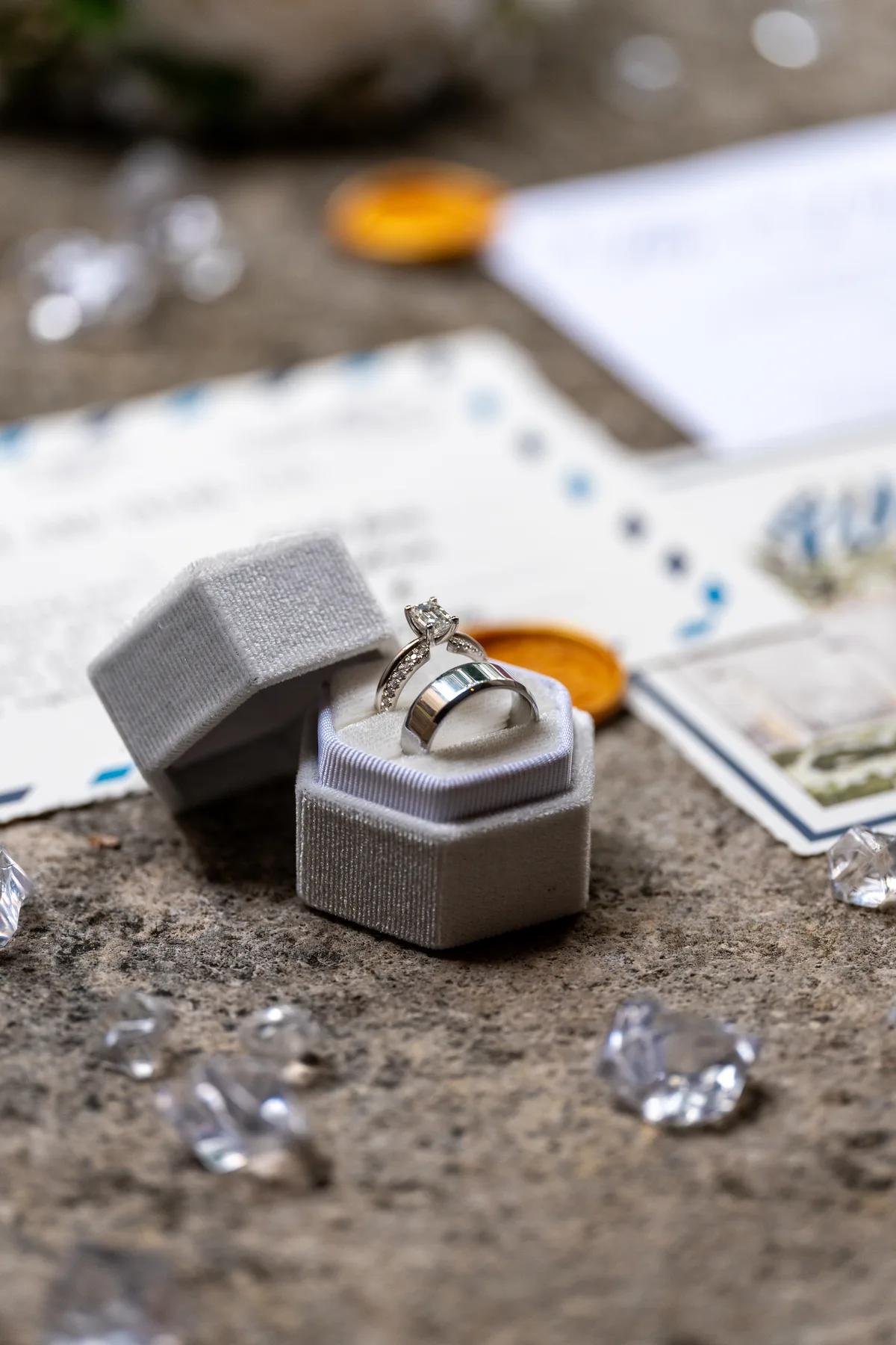 a close-up of a wedding ring and engagement ring in an open box surrounded by diamonds.