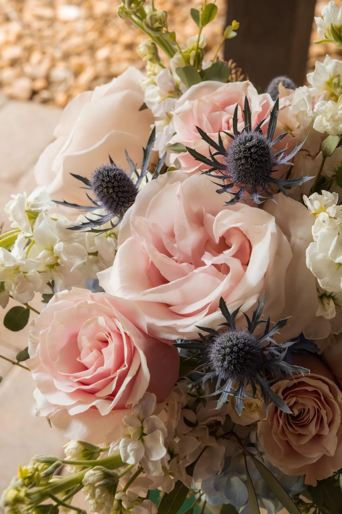 A beautiful bouquet of flowers with pink roses and blue spikes.