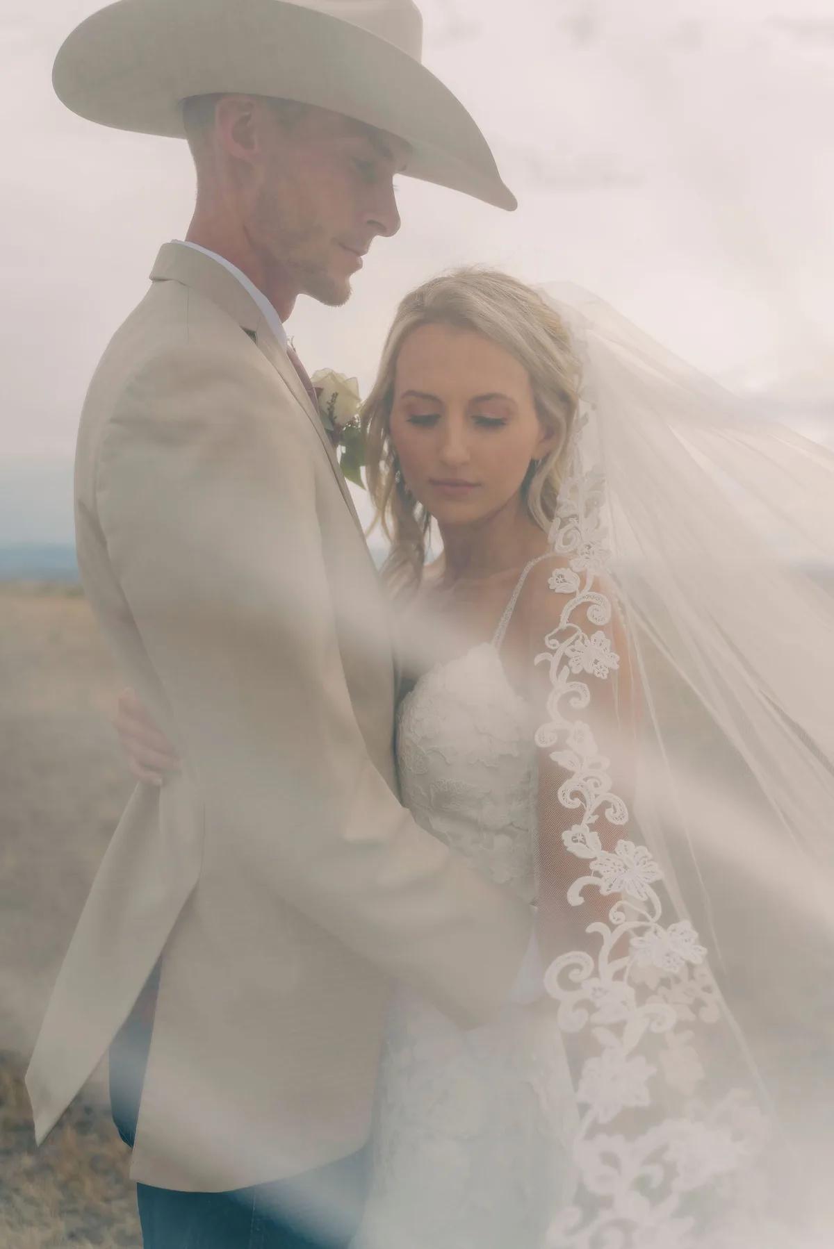 A bride and groom share a tender moment amidst a misty desert backdrop.