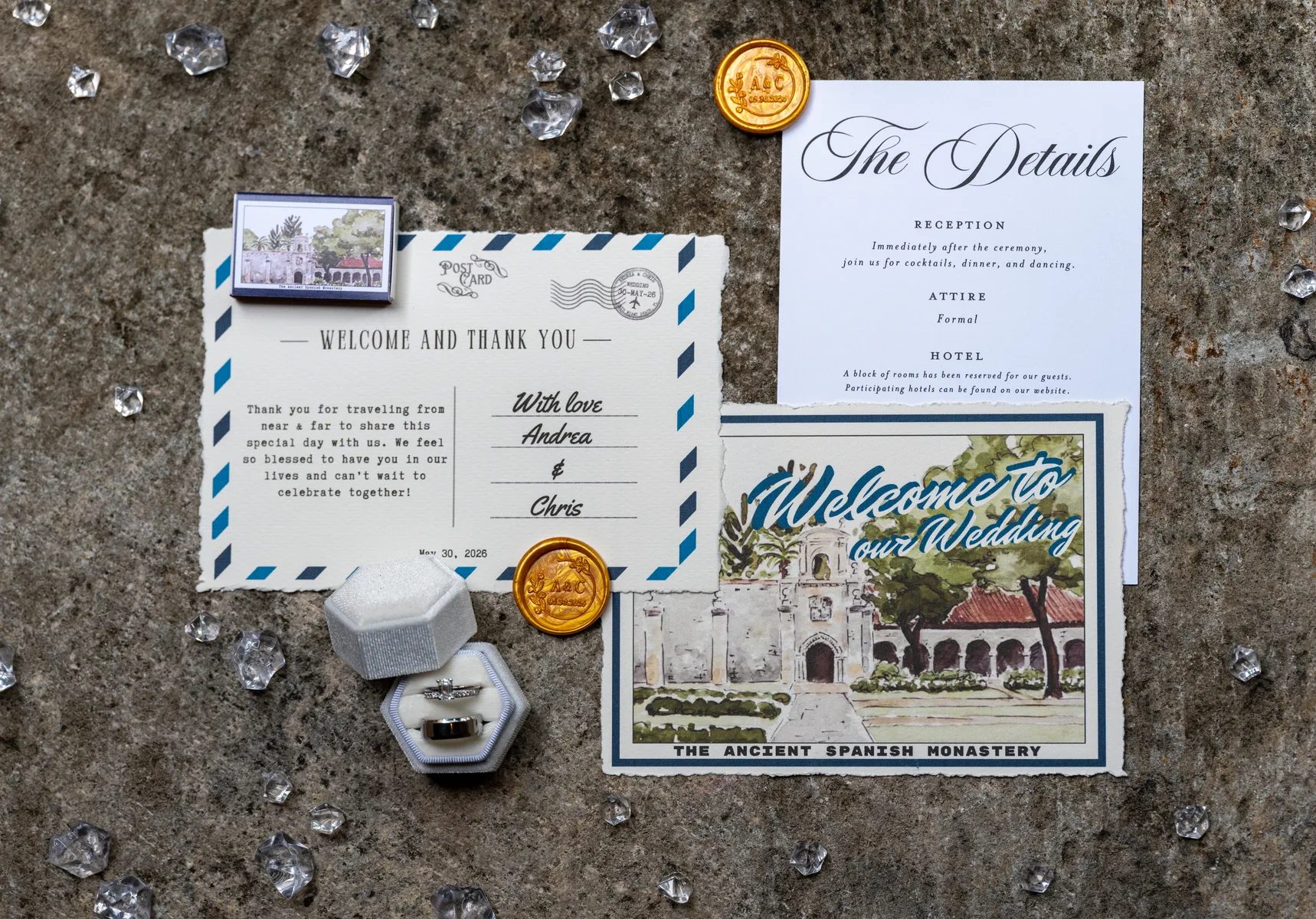 a wedding invitation and details card with a welcome message, rings in a box, and decorative elements on a textured surface.