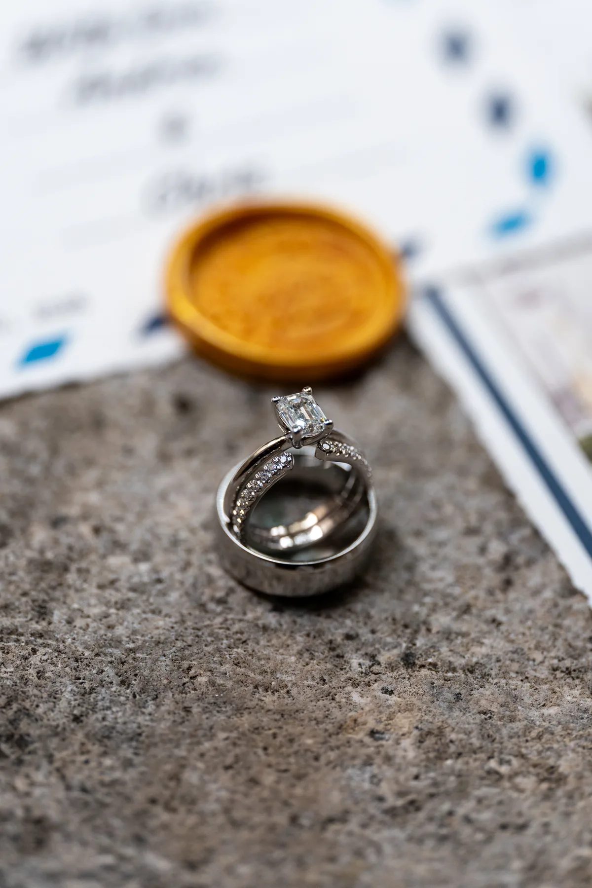 a close-up of two wedding rings with a diamond engagement ring placed on top of another.