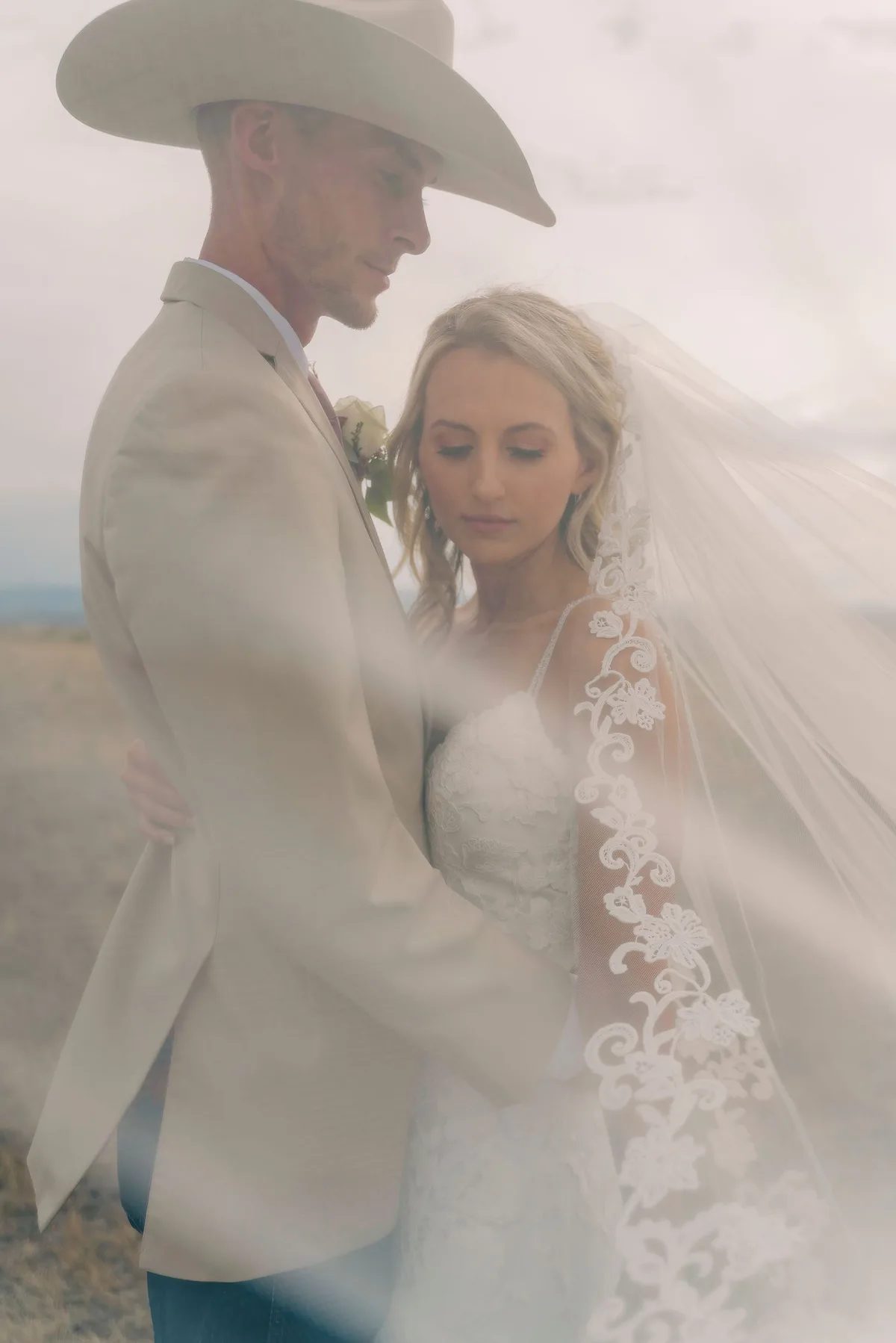 A bride and groom share a tender moment amidst a misty desert backdrop.