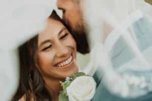A man and a woman are kissing with the man holding a rose behind his back.