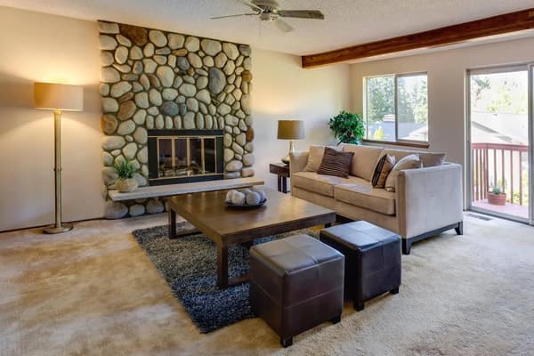 A living room with a stone fireplace and couches.