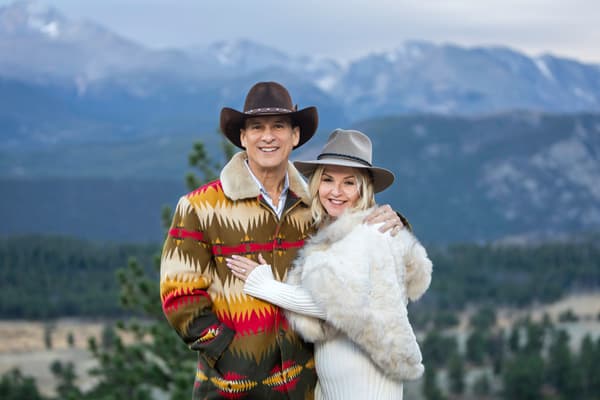 A couple embraces against a majestic mountain backdrop under soft, diffused lighting.