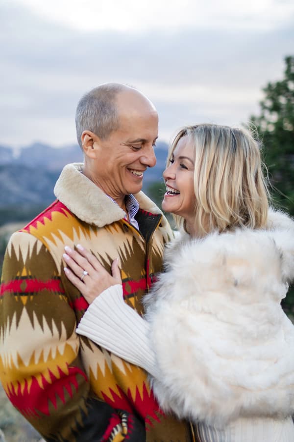A couple embraces warmly in a scenic mountain setting during the golden hour.