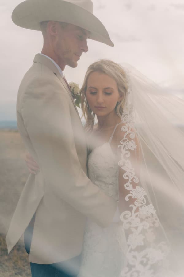 A bride and groom share a tender moment amidst a misty desert backdrop.