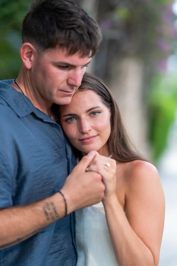 A tender moment between a couple in an outdoor garden setting during golden hour, with soft lighting and a romantic mood.