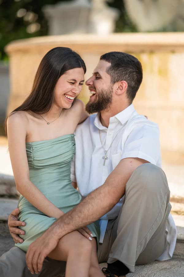 A couple shares a joyful moment in an outdoor setting during golden hour.