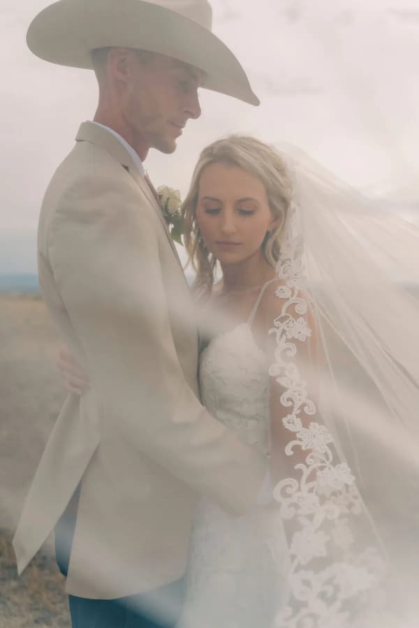 A bride and groom share a tender moment amidst a misty desert backdrop.